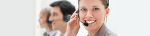 Mitarbeiter*innen mit Headsets am Arbeitsplatz, kommunizieren freundlich.