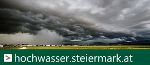 Link zur Webseite: www.hochwasser.steiermark.at Das Bild zeigt eine Landschaft mit einem Weizenfeld und am Himmel sind Gewitterwolken zu sehen.